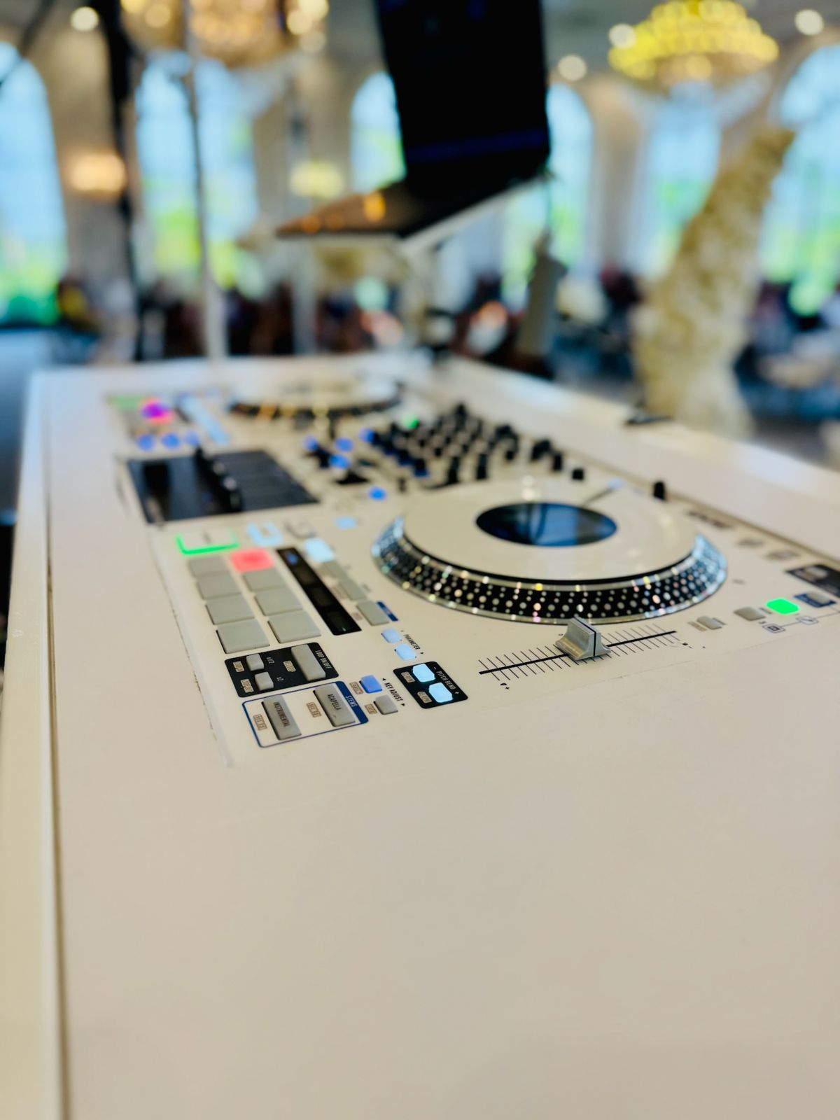 White DJ controller close-up with the ballroom chandeliers out of focus behind