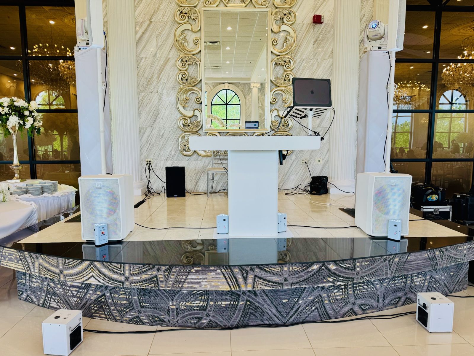 White booth, white speakers and moving heads set on a ballroom stage with gold mirror and marble wall