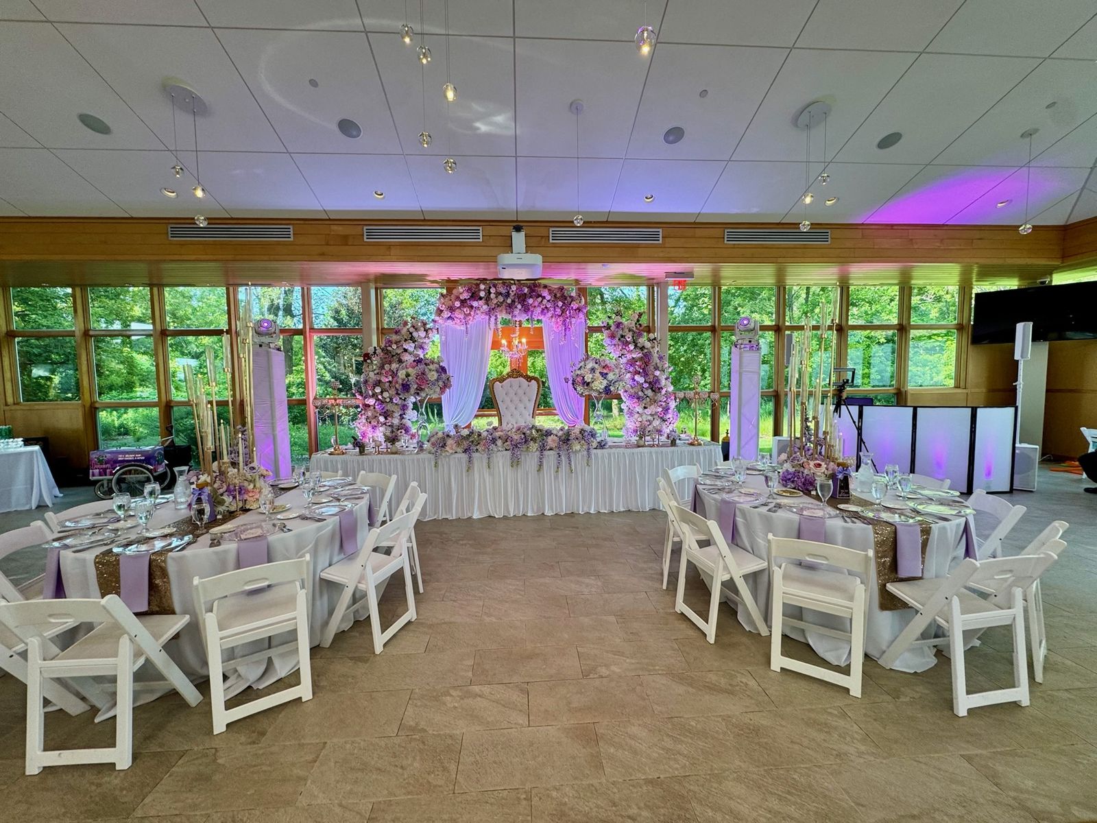 Lavender and purple uplit reception room with a floral sweetheart table and moving heads